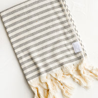 Abyss Stripe: A turkish hand towel in natural with black stripes with natural fringed trim.