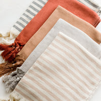 1: Layered turkish hand towels in a mix of solid and striped colors.