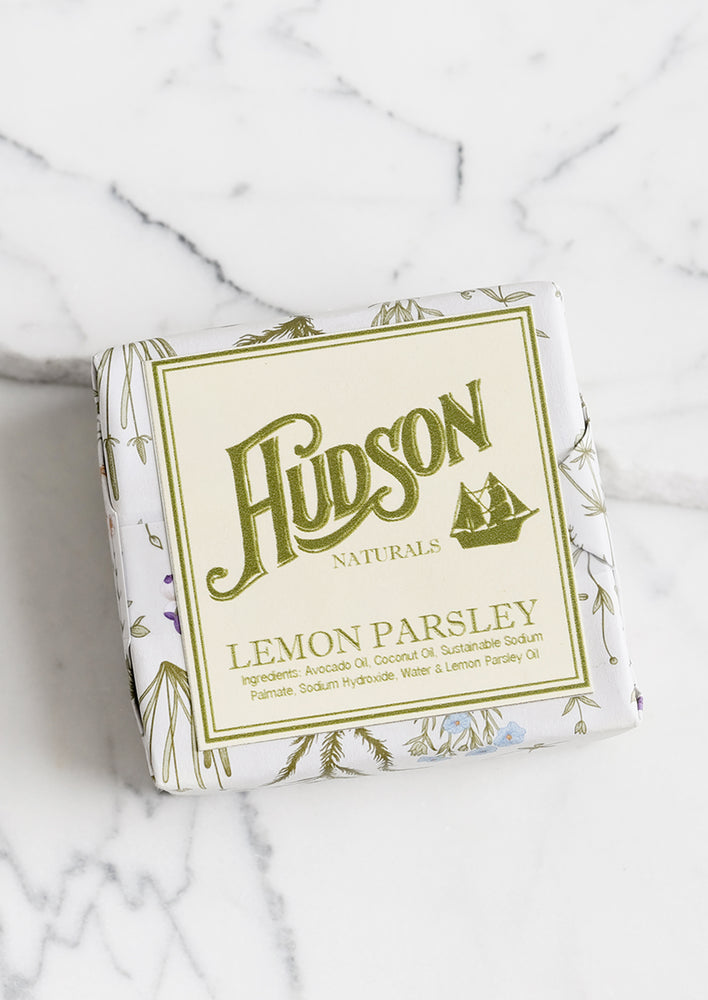 A square bar of soap in botanical printed packaging in Lemon Parsley scent.