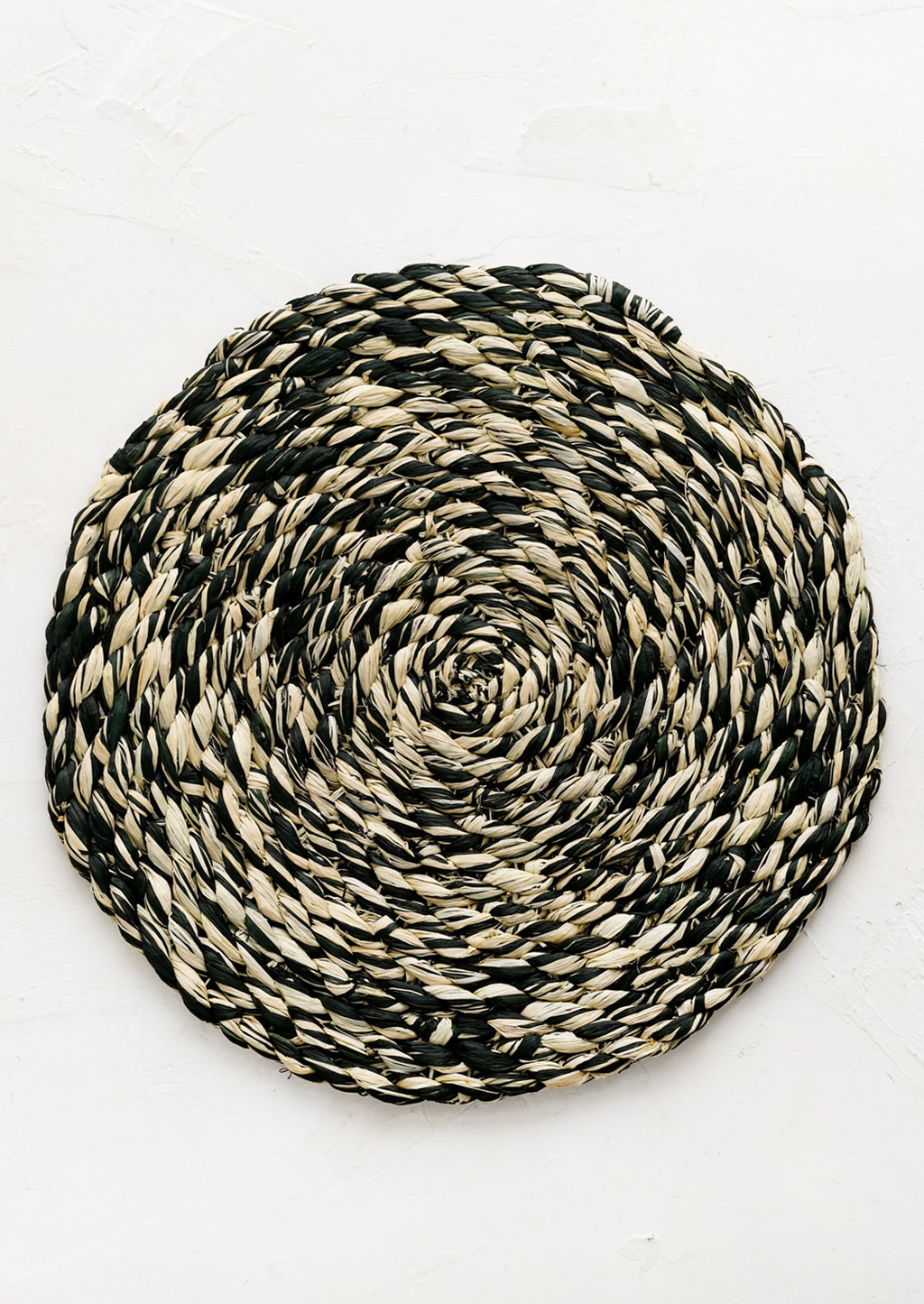 Deep Forest: A round woven raffia placemat in natural and dark forest green.