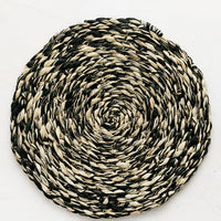Deep Forest: A round woven raffia placemat in natural and dark forest green.