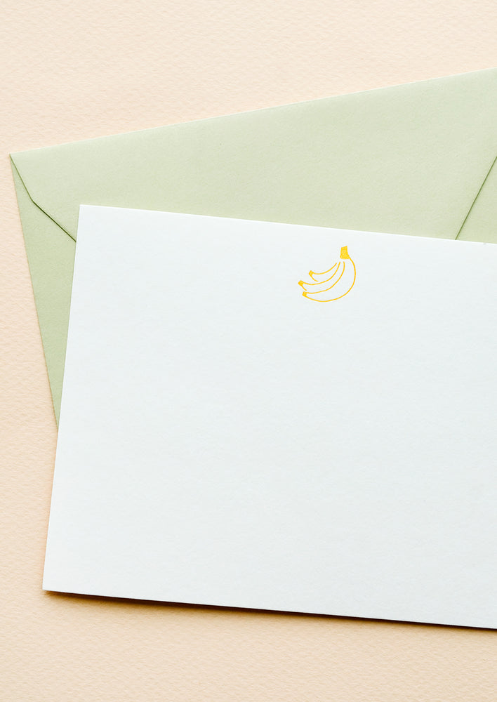 A mint colored envelope with white notecard and small icon of a bunch of bananas printed at top.