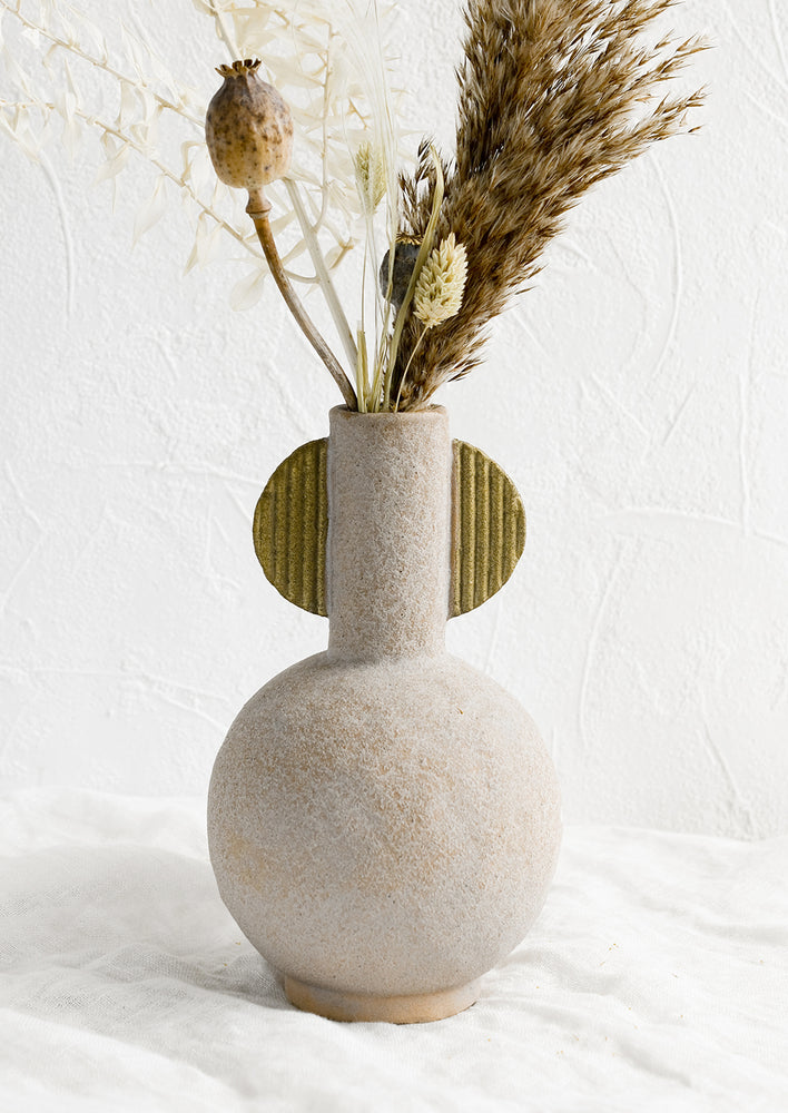 A sculptural ceramic vase with dried flowers.