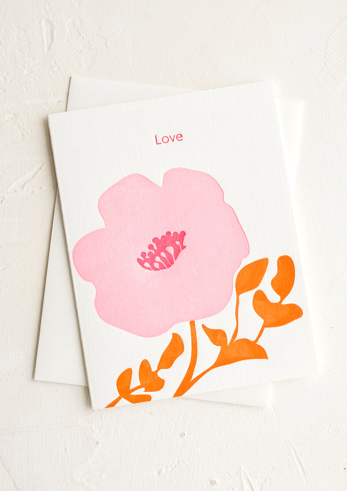 A greeting card with pink and orange letterpress flower and "LOVE" text at top.