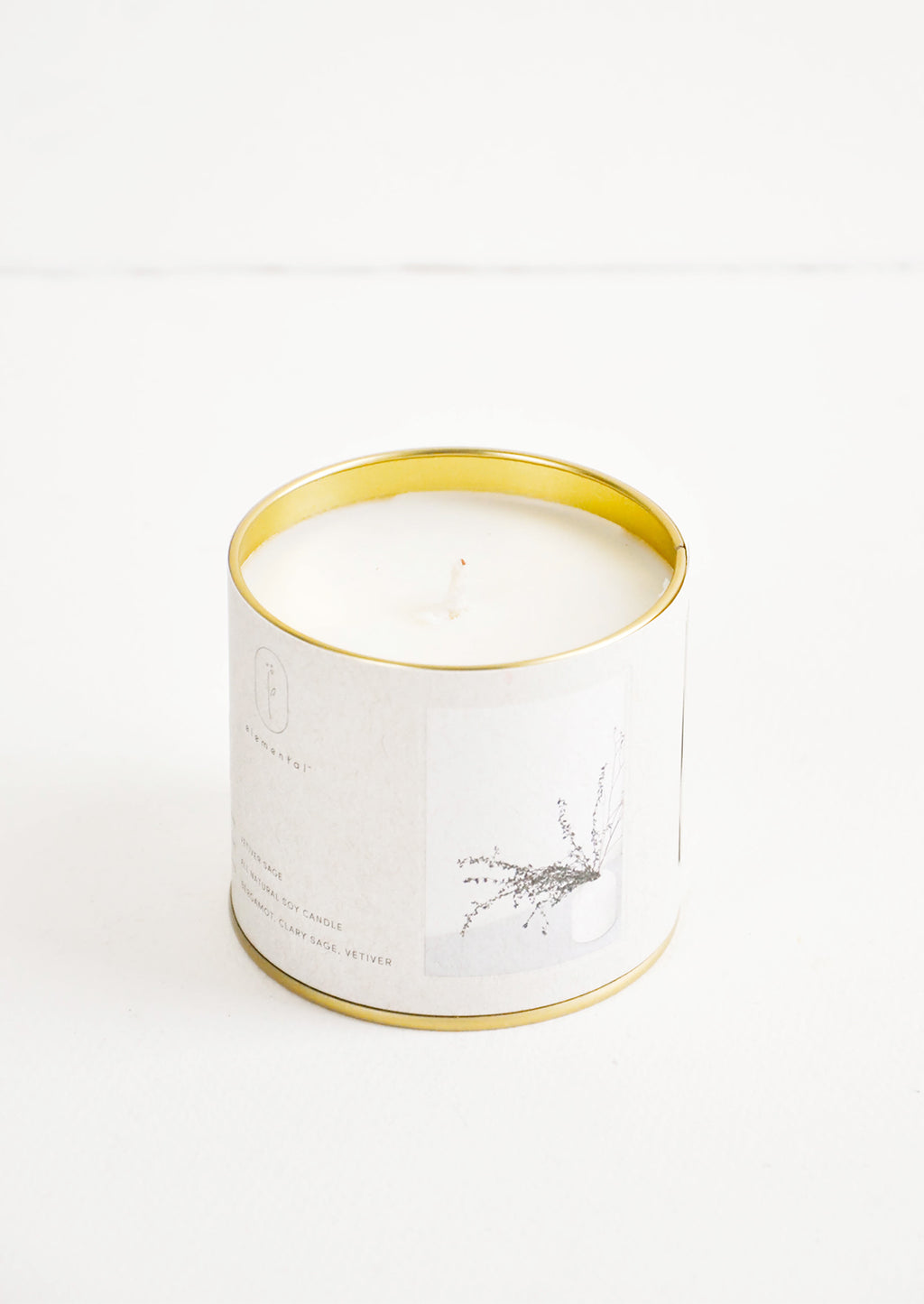 Vetiver Sage: A candle in a brass tin with a gray label featuring a picture of grasses.