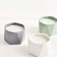 1: Three small candles in faceted ceramic vessels in assorted colors.