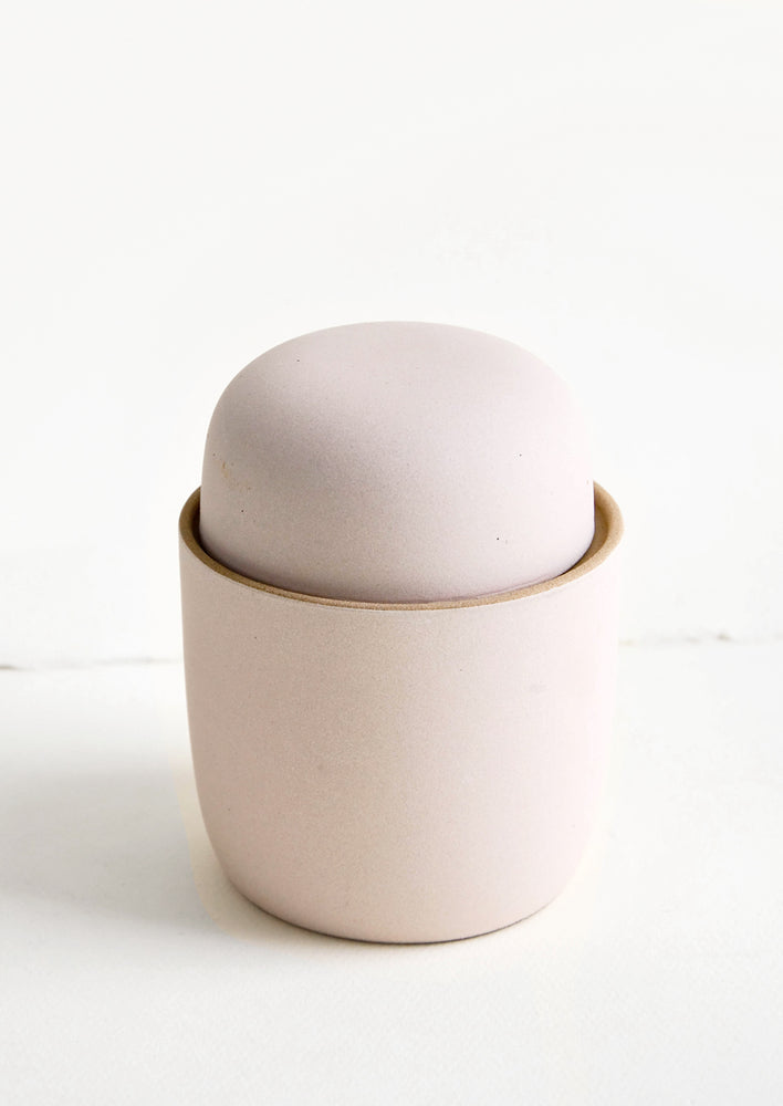 Scented candle in pale pink colored reusable matte ceramic vessel with lid