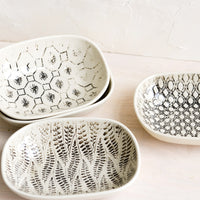 1: Small oval ceramic dishes in assorted black and white patterns.