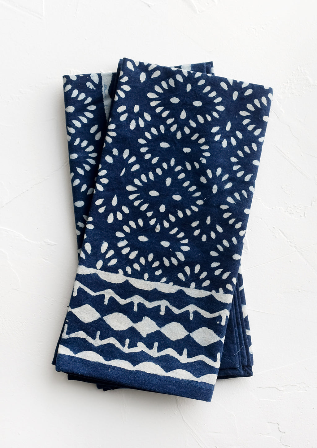 1: A pair of indigo napkins with white block printed pattern.