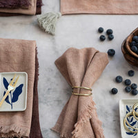 5: A styled table scene with textiles, ceramics and gold napkin rings.