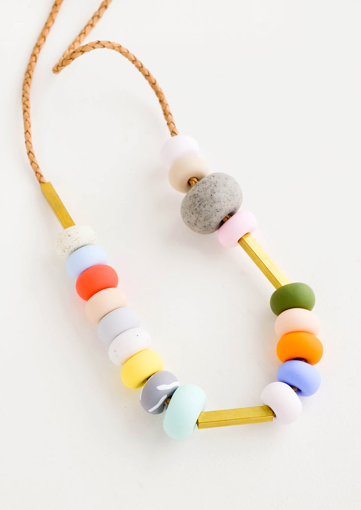 Round clay beads in a mix of colors, textures and sizes strung on leather cord
