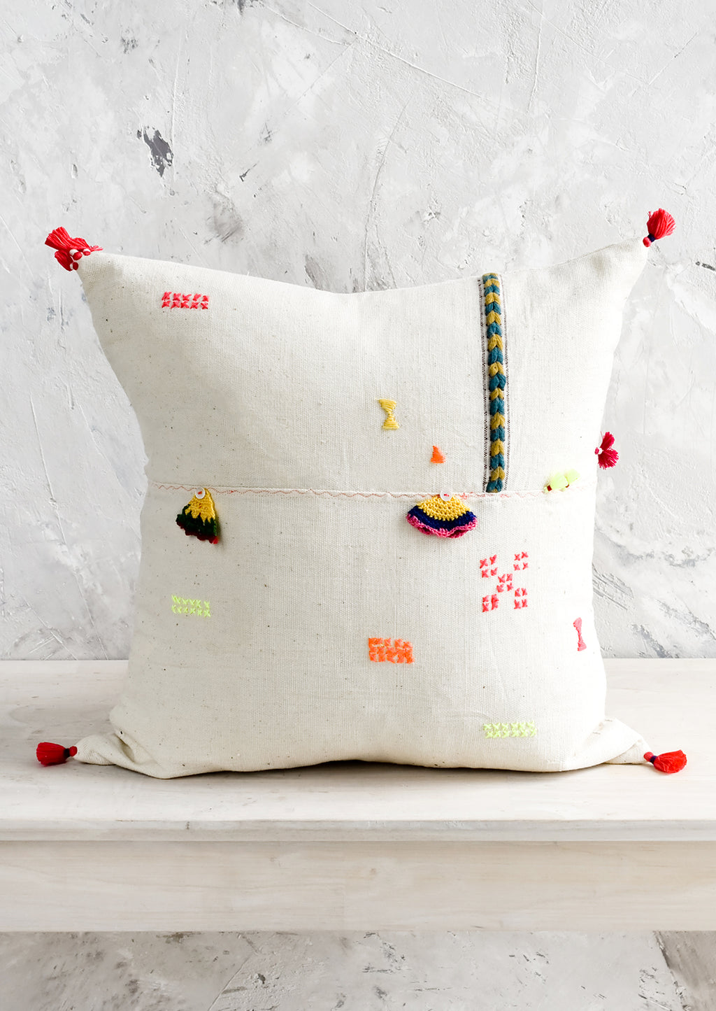 1: A square throw pillow with neon embroidery and applique detailing.