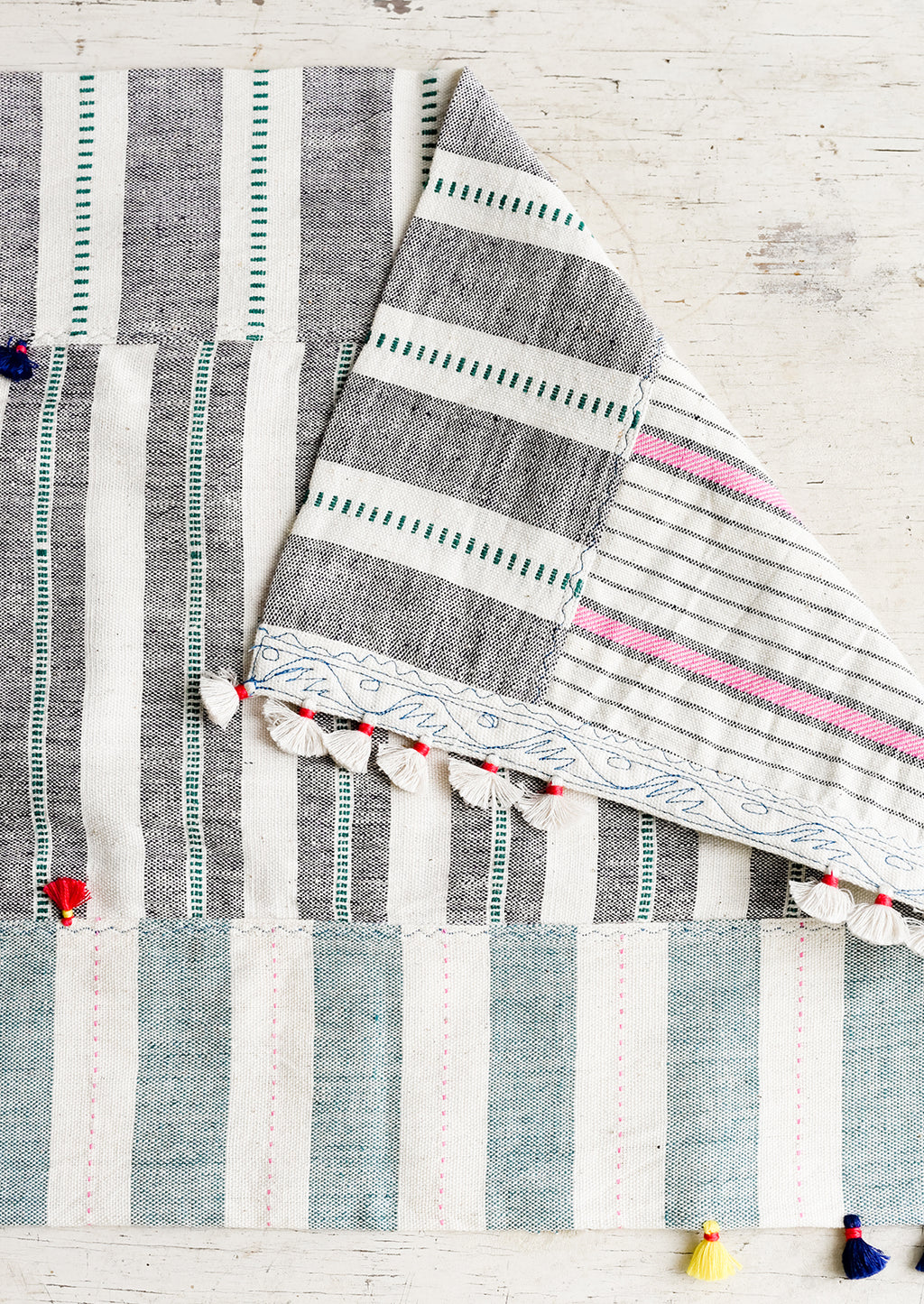 1: A madras stripe placemat in multicolor with tassel detail.