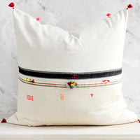 1: A square throw pillow with neon embroidery and tassel detailing.