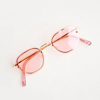 2: Sunglasses with light pink tinted plastic lenses and a metal frame behind the lens