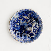 1: A round ceramic dish with floral imprint and blue glaze.