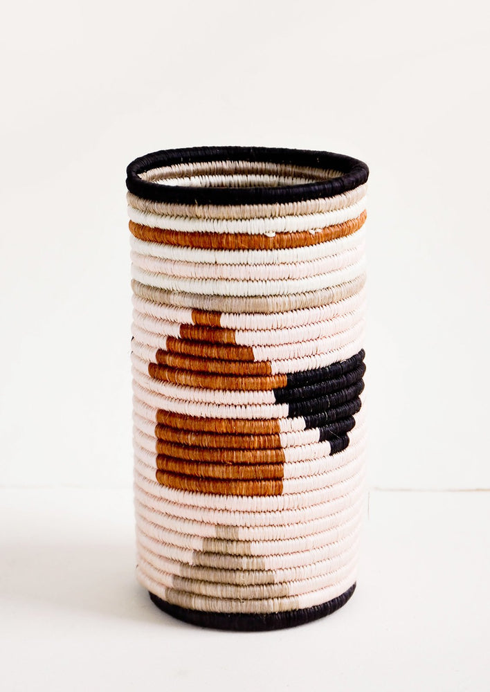 Tall vase made of woven natural grass in colorful geometric pattern