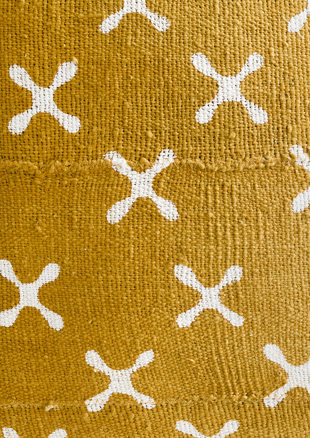 2: Mustard colored mudcloth fabric with white X pattern.