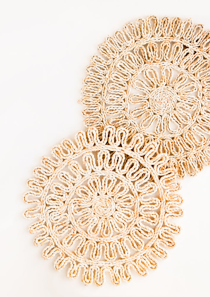 Set of two round placemats in natural straw in a decorative woven pattern