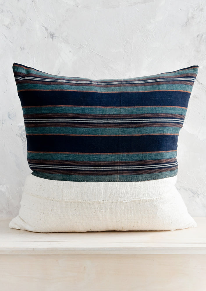 A square throw pillow with half striped japanese hemp, half natural mudcloth.