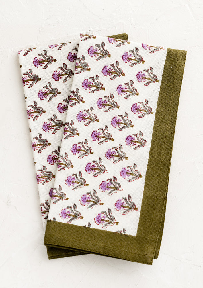 A pair of block printed floral napkins in olive and purple.