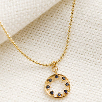 Sapphire: A gold necklace with circular pendant with blue inner stones.