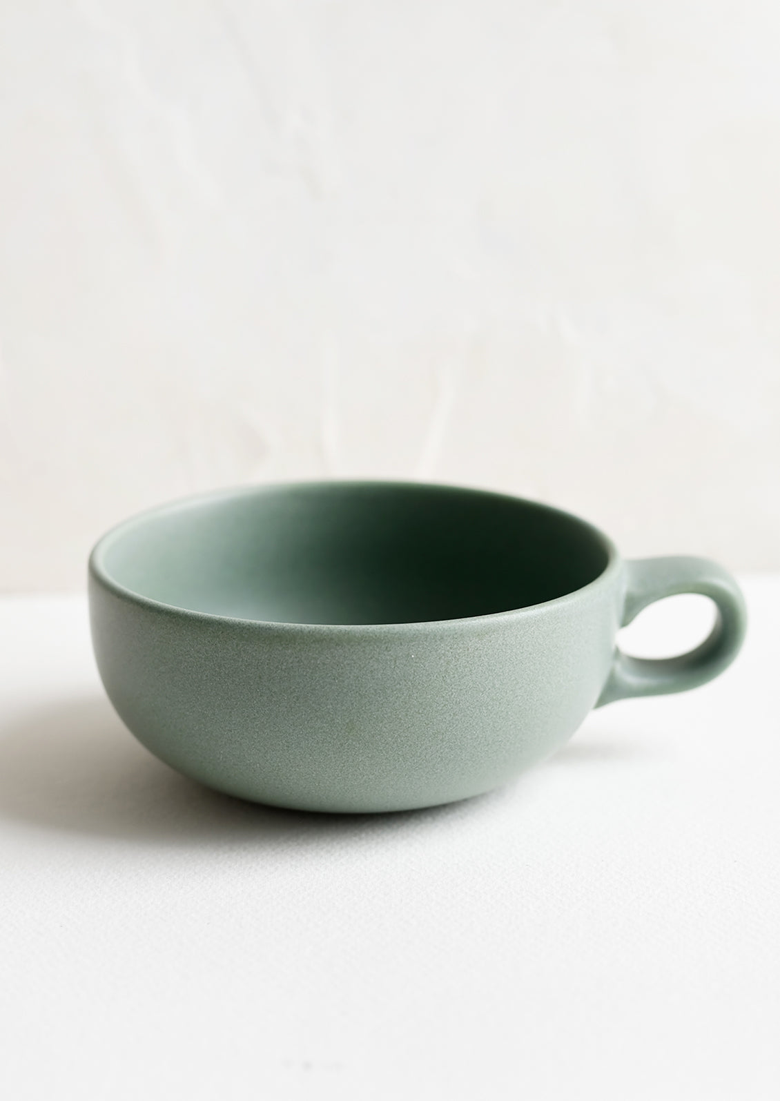 A ceramic bowl mug in juniper green.