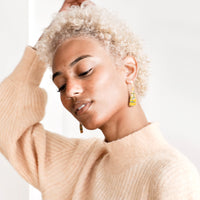 3: Model wears yellow triangle shaped beaded earrings and peach sweater.