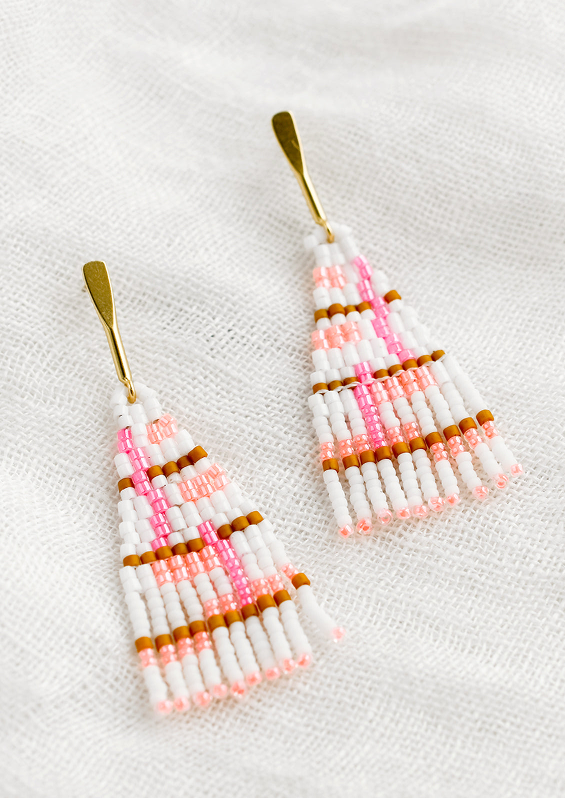 A pair of beaded earrings in white and neon pink colorway.