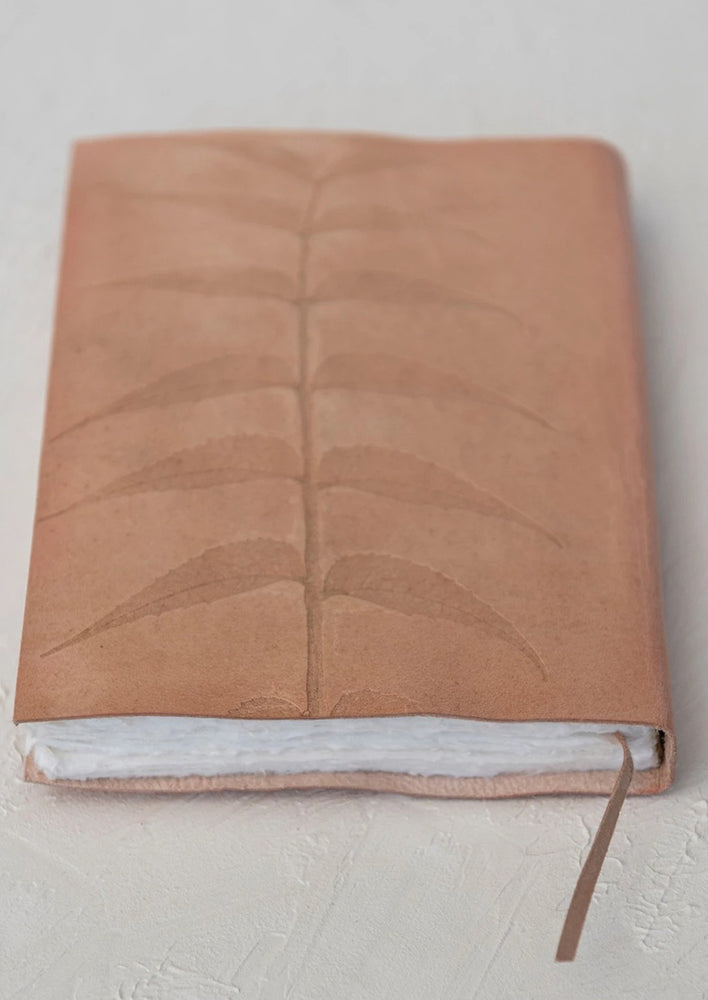 A natural leather journal with embossed leaf design.