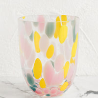 Multi / Sparse: A handmade speckled glass juice cup with teal, yellow and pink spots.