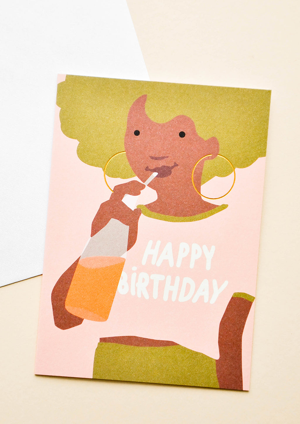 1: Greeting card with illustration of girl with green hair, drinking orange soda with "Happy Birthday" written on her pink t-shirt. Shown with white envelope.