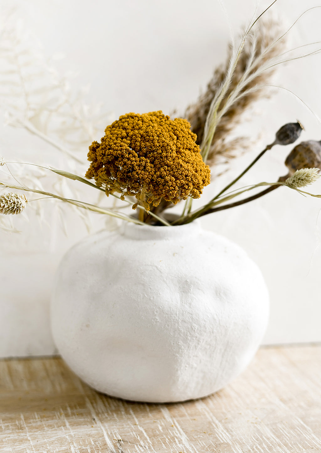 3: A white ceramic vase with dried flowers.