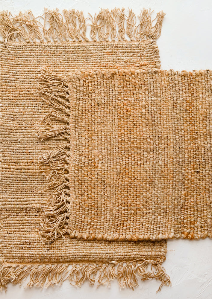Two jute placemats with fringed trim.