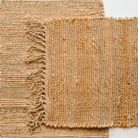 1: Two jute placemats with fringed trim.