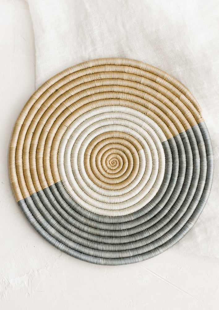1: A woven trivet in tan and dusty blue.