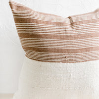 1: A throw pillow with top half in brown & ivory striped fabric and bottom half in natural mudcloth.
