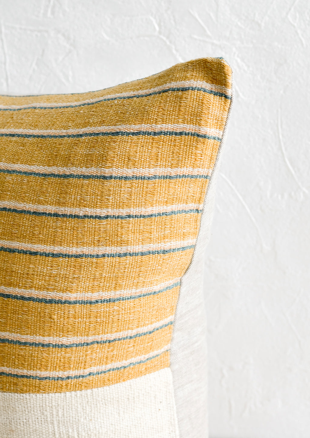 5: A throw pillow with top half in mustard, ivory & teal striped fabric with natural linen back.
