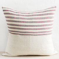 2: A throw pillow with top half in ivory, red and blue striped fabric and bottom half in natural mudcloth.