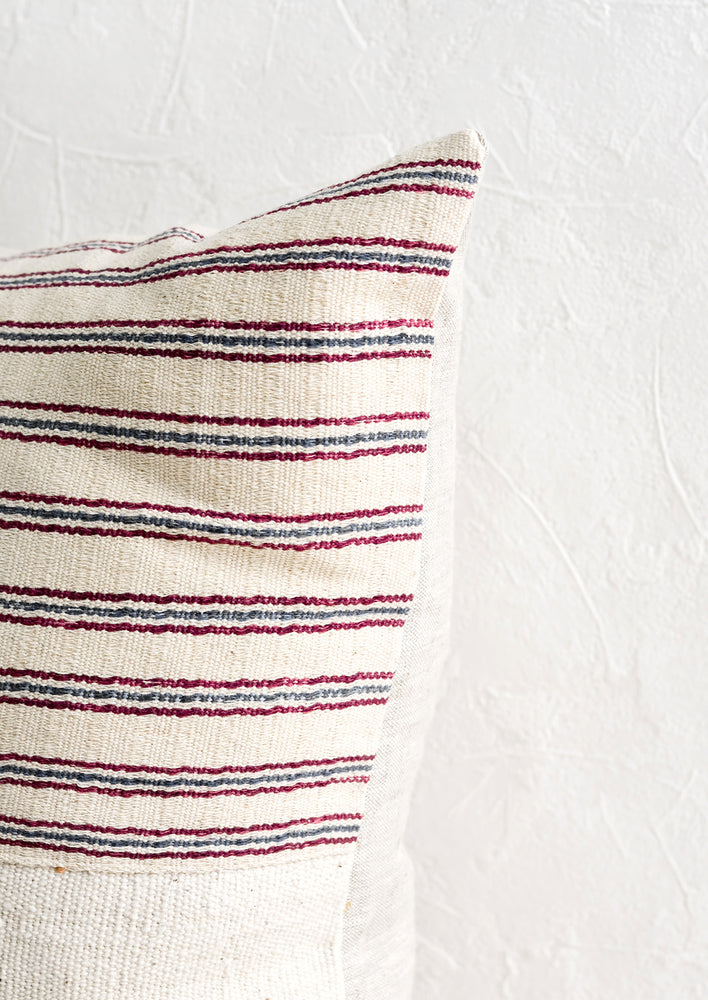 5: A throw pillow with top half in ivory, red and blue striped fabric and natural linen back.