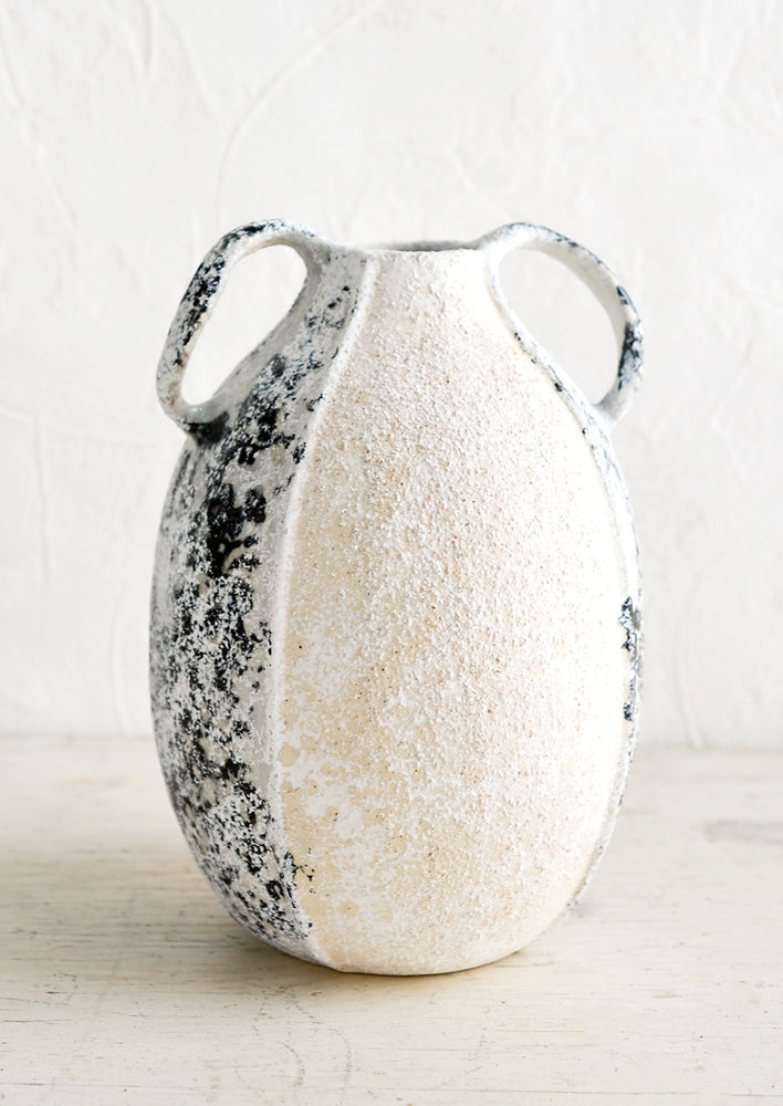 A distressed ceramic vase in tall shape with side handles.