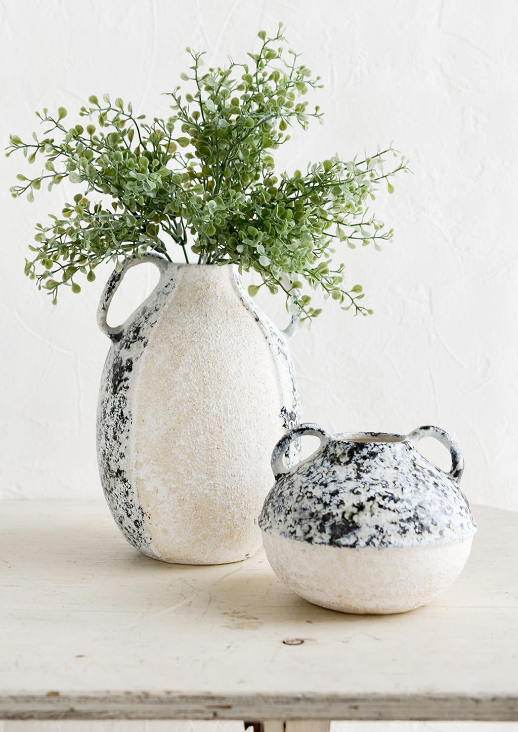 1: Distressed ceramic vases in ivory and grey, sitting on a table.