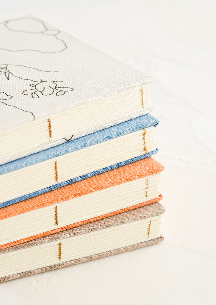 A stack of cloth journals with hand-bound seams.