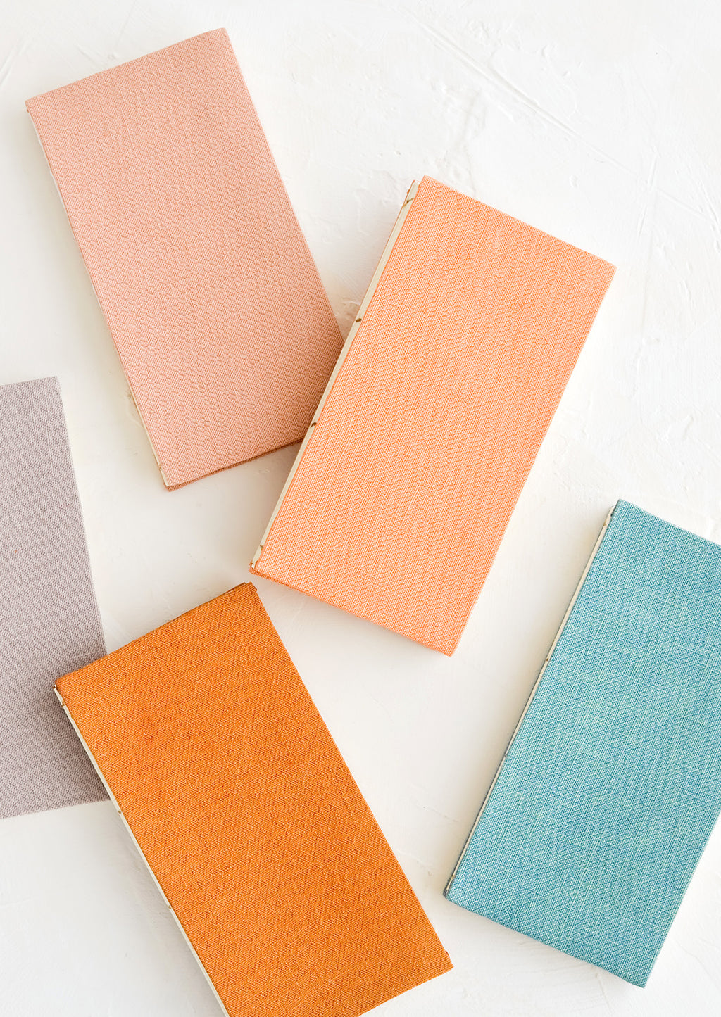 1: Five cloth-covered notebooks in naturally dyed hues.