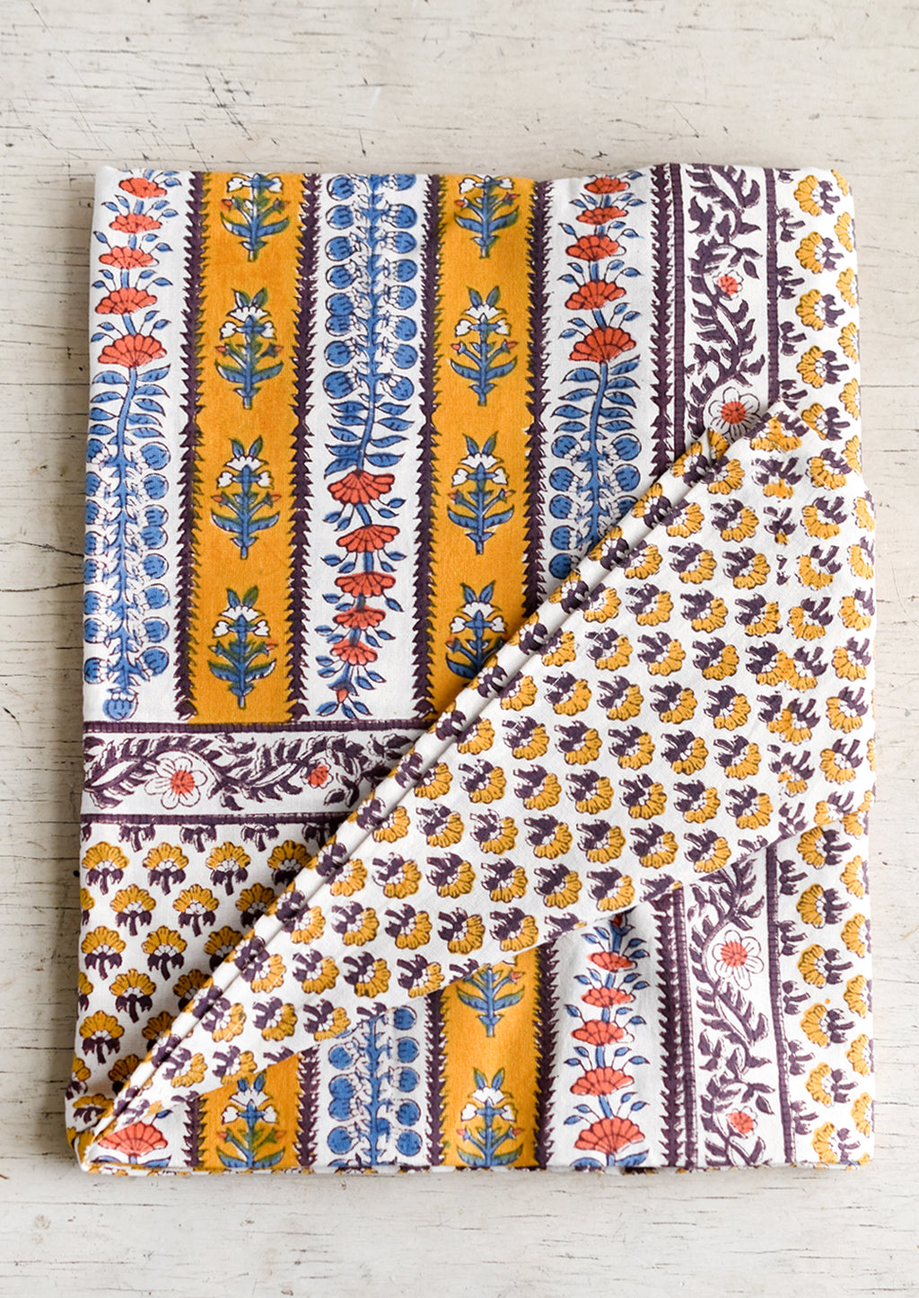2: A stripe floral print tablecloth in marigold, purple and blue.