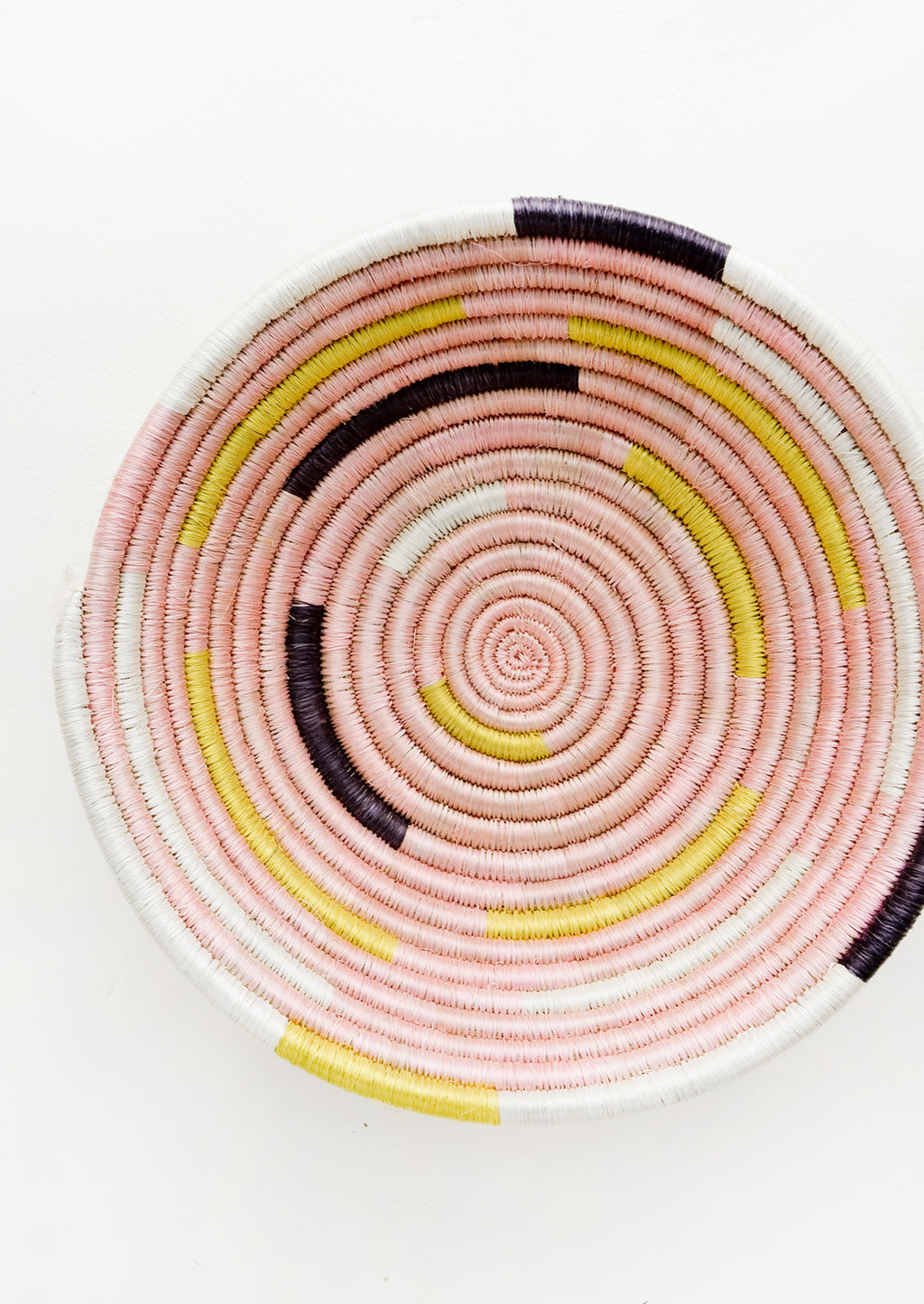 1: Round bowl made from woven sweetgrass in pink, white, yellow and black modern spiral design.