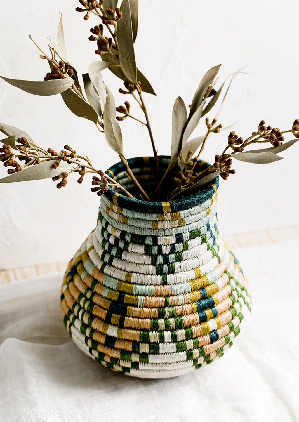 1: A woven sweetgrass vase holding dried eucalyptus.