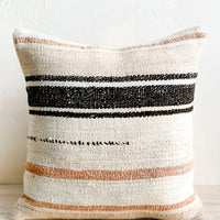 1: A square throw pillow in ivory with black and peach/clay stripes.