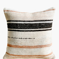 2: A square throw pillow in ivory with black and peach/clay stripes.