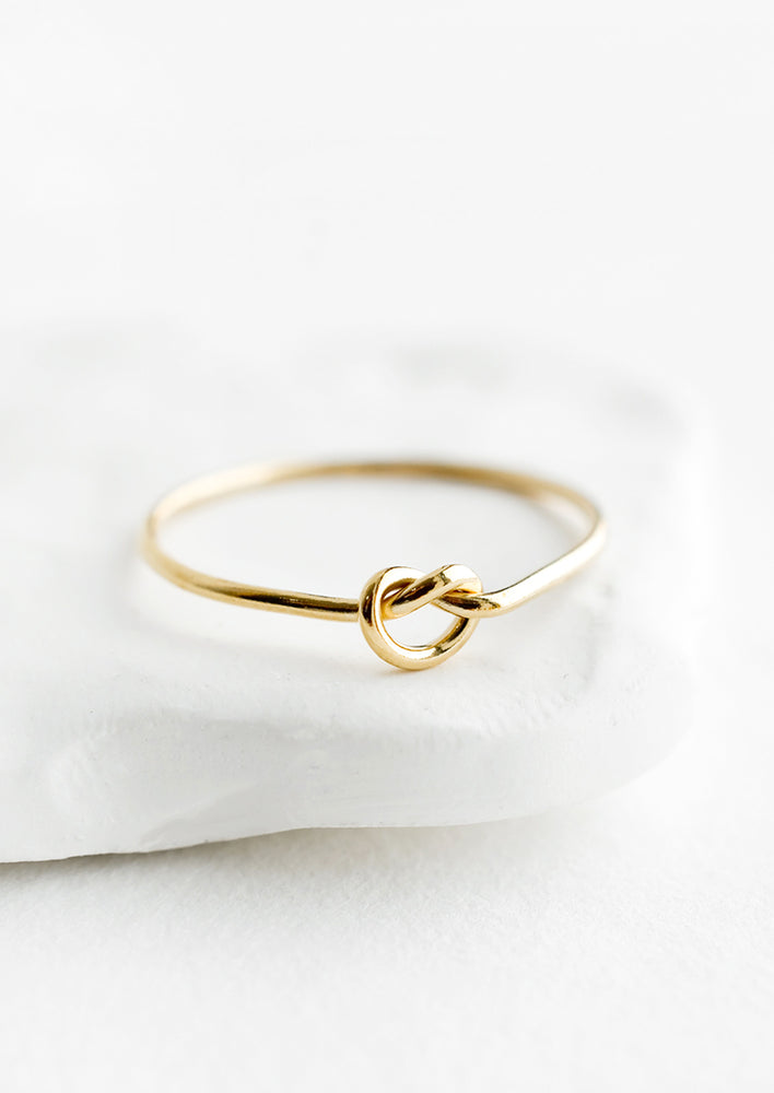 A simple gold ring designed for stacking, with single knot detailing at front.